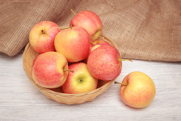 Tasty red and yellow apple fruits on wooden white background in basket