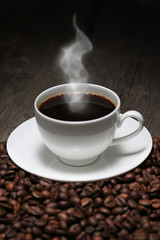 Cup of coffee with steam and coffee beans