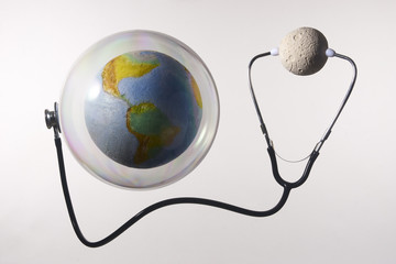 Moon diagnoses the earth in bubble with a stethoscope. Climate change concept; Isolated on grey background. With copy space text. Studio Shot.
