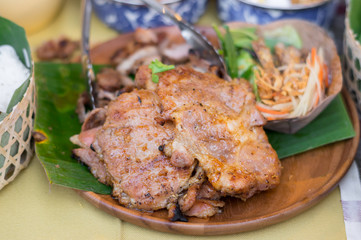 Grilled pork on wooden plate in market.