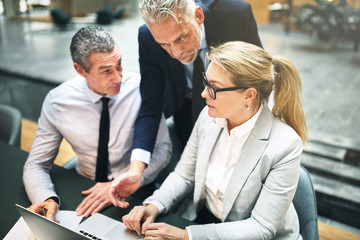 Three mature businesspeople discussing work together in an offic