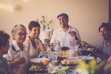 happy group of different ages people celebrating and having fun together in friendship at home or restaurant. cheering and toasting with cocktails and alchool. smile and enjoy the party with adult