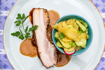 Schweinebraten vom Schweine Bauch und Kartoffelsalat mit Gurken  und Sauce zum essen 