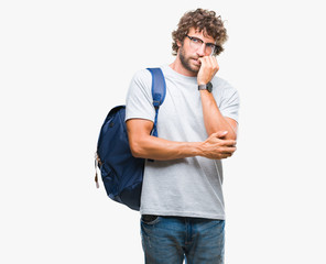 Handsome hispanic student man wearing backpack and glasses over isolated background looking stressed and nervous with hands on mouth biting nails. Anxiety problem.