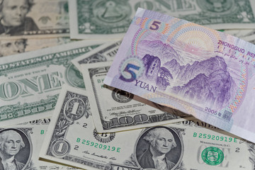 Banknote of five Chinese yuan against background of american dollars