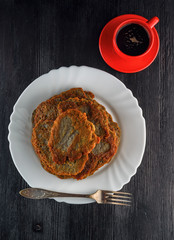 a stack of potato pancakes on a white plate on a wooden background. Home kitchen.