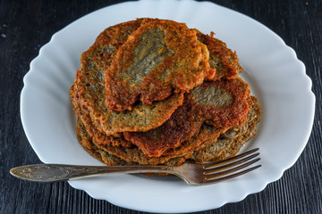 a stack of potato pancakes on a white plate on a wooden background. Home kitchen.