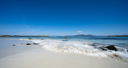 Fototapeta na wymiar Waves on the beautiful white sands of the North Beach, Isle of Iona, Scotland, UK, on a sunny day
