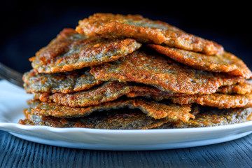 a stack of potato pancakes on a white plate on a wooden background. Home kitchen.