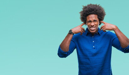 Afro american man over isolated background covering ears with fingers with annoyed expression for...