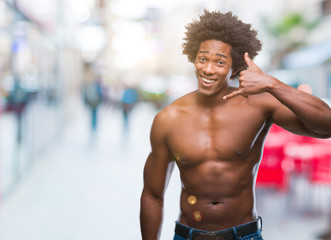 Fototapeta na wymiar Afro american shirtless man showing nude body over isolated background smiling doing phone gesture with hand and fingers like talking on the telephone. Communicating concepts.