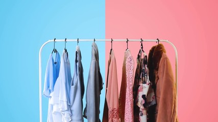 Women's clothing on a white clothes hanger on pink and blue pastel colors background.