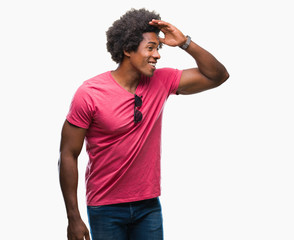 Afro american man over isolated background very happy and smiling looking far away with hand over head. Searching concept.