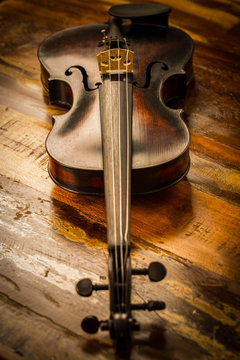Old violin in vintage style on wood background
