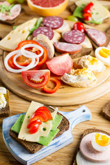 Breakfast table with cheese sandwiches, sausage, vegetables, hard boiled eggs and fruits
