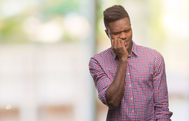 Young african american man over isolated background looking stressed and nervous with hands on mouth biting nails. Anxiety problem.