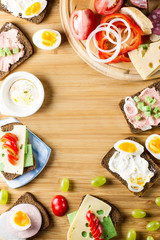 Breakfast table with cheese sandwiches, sausage, vegetables, hard boiled eggs and fruits