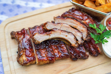 gegrillte Marinierte Spare Ribs mit Country Farmer Potaoes Kartoffeln auf einem Holzbrett mit Dips