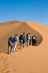 Group of people climbing sand dunes