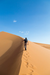 One person climbing big dune in the desert