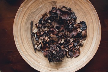 In the wooden plate are lined with beautiful fruit cones, ears of grass, dried fruit details and plant branches. On the edge of the plate lies a ball woven from the vine of a tree.