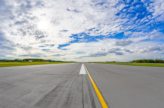 Airport runway to in horizon and picturesque clouds in the blue sky.