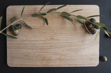 olive tree branch with olives on wooden cutting Board