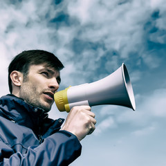 businessman talking in a megaphone against the sky.