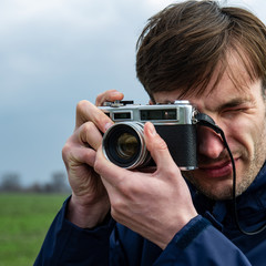 photographer takes a picture with a film camera on an open air.