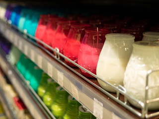 Many multicolored colorful red orange yellow paraffin stick candles arranged in black shelves lying...