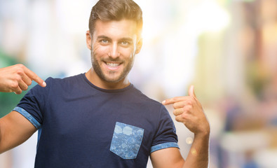 Young handsome man over isolated background looking confident with smile on face, pointing oneself...