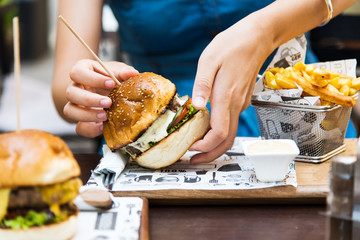 Girl eating burger in the restaurant - obrazy, fototapety, plakaty
