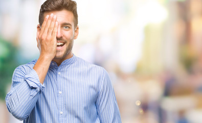 Obraz premium Young handsome man over isolated background covering one eye with hand with confident smile on face and surprise emotion.