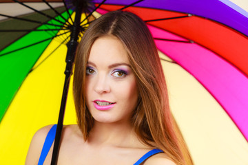 Woman standing under colorful rainbow umbrella