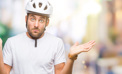 Young handsome man wearing cyclist safety helmet over isolated background clueless and confused...