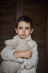 A young boy, a serious look is dressed in a knitted white sweater. Portrait