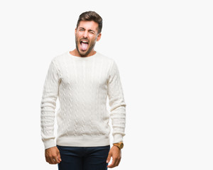 Young handsome man wearing winter sweater over isolated background sticking tongue out happy with funny expression. Emotion concept.