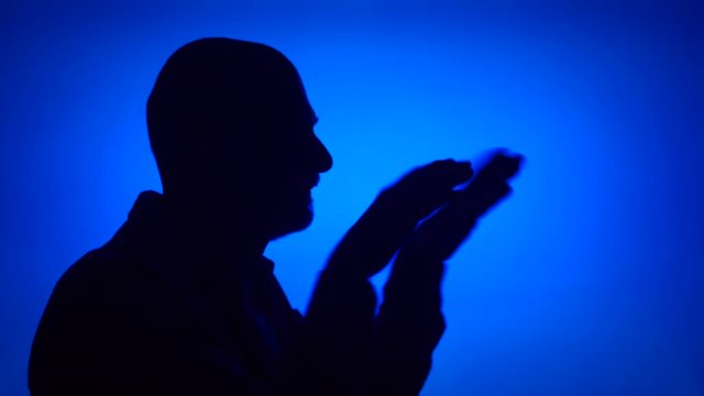 Silhouette of happy senior man dancing silly on blue background. Male's face in profile having fun. Black contur shadow of grandfather's half-face fooling around