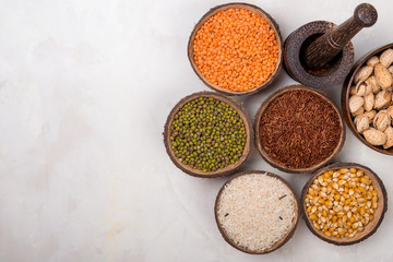 cereals, seeds, beans, grains in a bowls on white table, top view