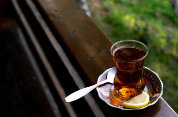 Turkish tea on a wooden board. blurred foliage background. Lemon tea