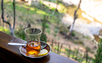 Turkish tea on a wooden board. blurred foliage background. Lemon tea. Half empty hot tea