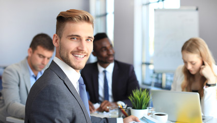 Businessman with colleagues in the background in office.