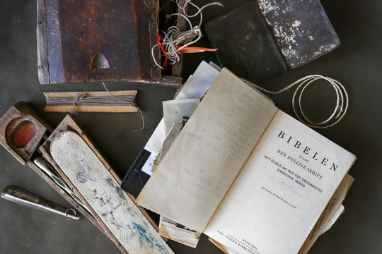 Old Bible on Norwegian language , homemade school pencil case and fishing equipment on the black background 