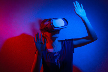 A cheerful girl with her hands up in virtual reality glasses.