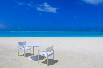 Fototapeta na wymiar Table and chair on the white sandy beach