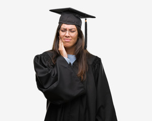 Young hispanic woman wearing graduated cap and uniform touching mouth with hand with painful expression because of toothache or dental illness on teeth. Dentist concept.