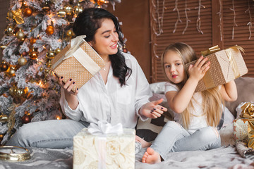 Young pretty mother and her little daughter sharing Christmas presents