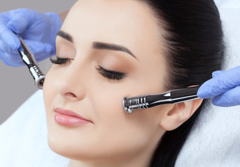 The cosmetologist makes the Microdermabrasion procedure of the facial skin of a beautiful, young...