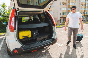 man putting bags in car trunk. ready for car travel