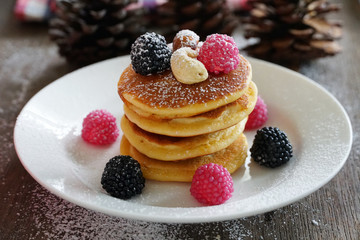 Pancake topping with berries and nut with background gift and pine cone under christmas tree, holiday party dessert.